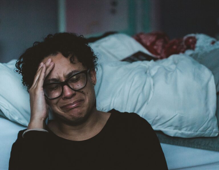 Personne pleurant à côté de son lit à cause du stress et de l'épuisement.