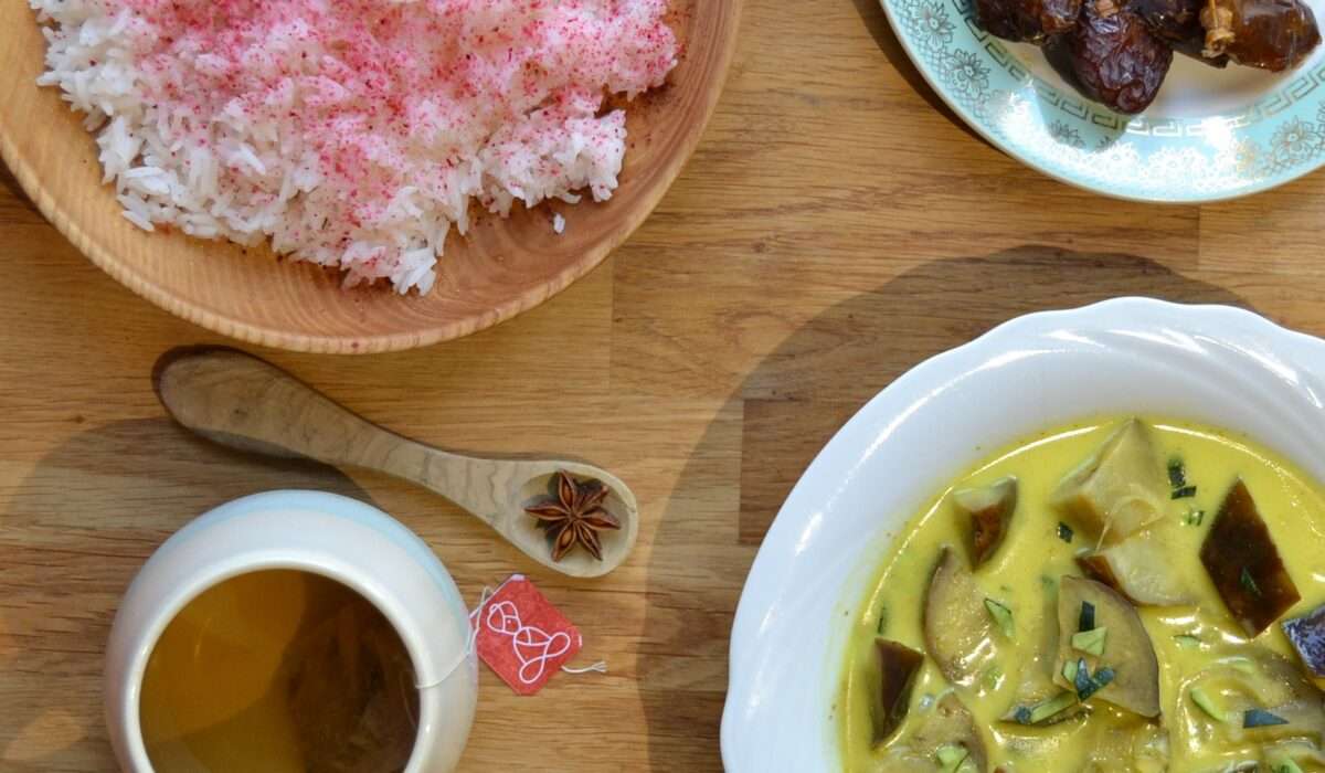 Assiettes vues par le haut : riz safrané, dattes, curry d'aubergines et coco. Une tasse de tisane Atma accompagne le repas